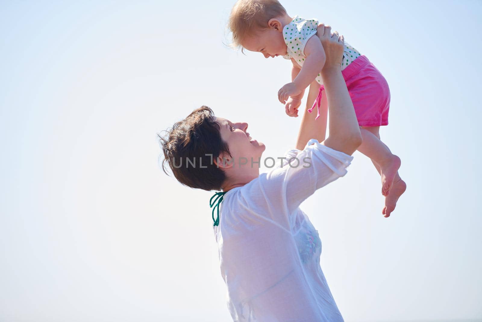 happy mom and baby on beach  have fun while learning to walk and  make first steps