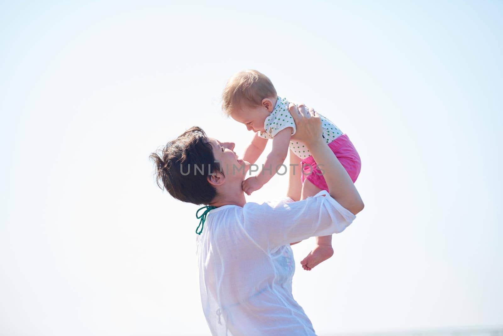 happy mom and baby on beach  have fun while learning to walk and  make first steps