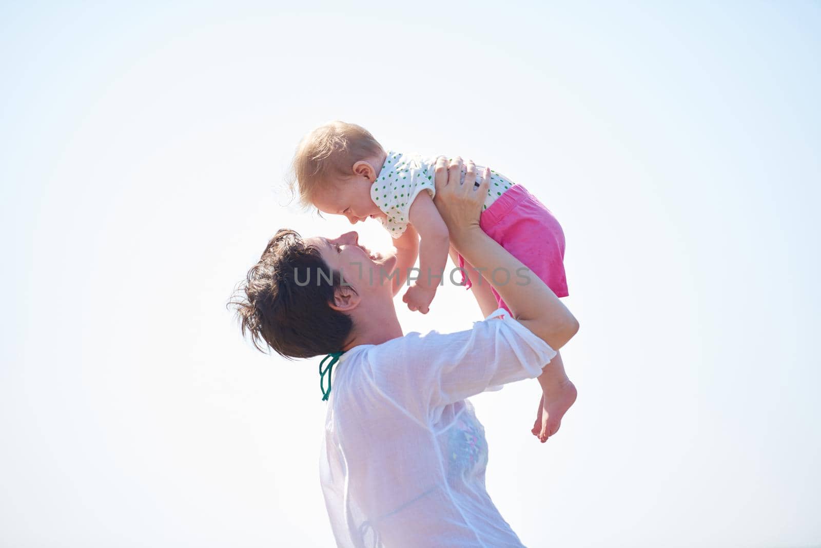 happy mom and baby on beach  have fun while learning to walk and  make first steps