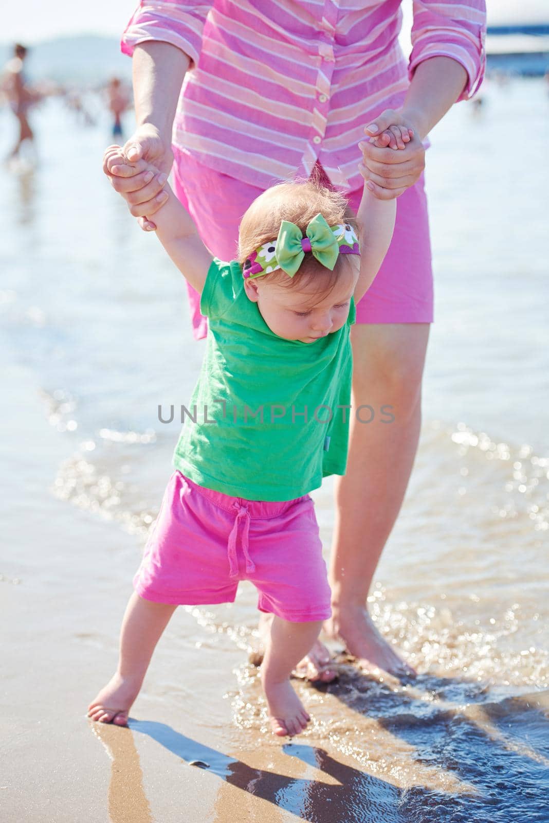 happy mom and baby on beach  have fun while learning to walk and  make first steps