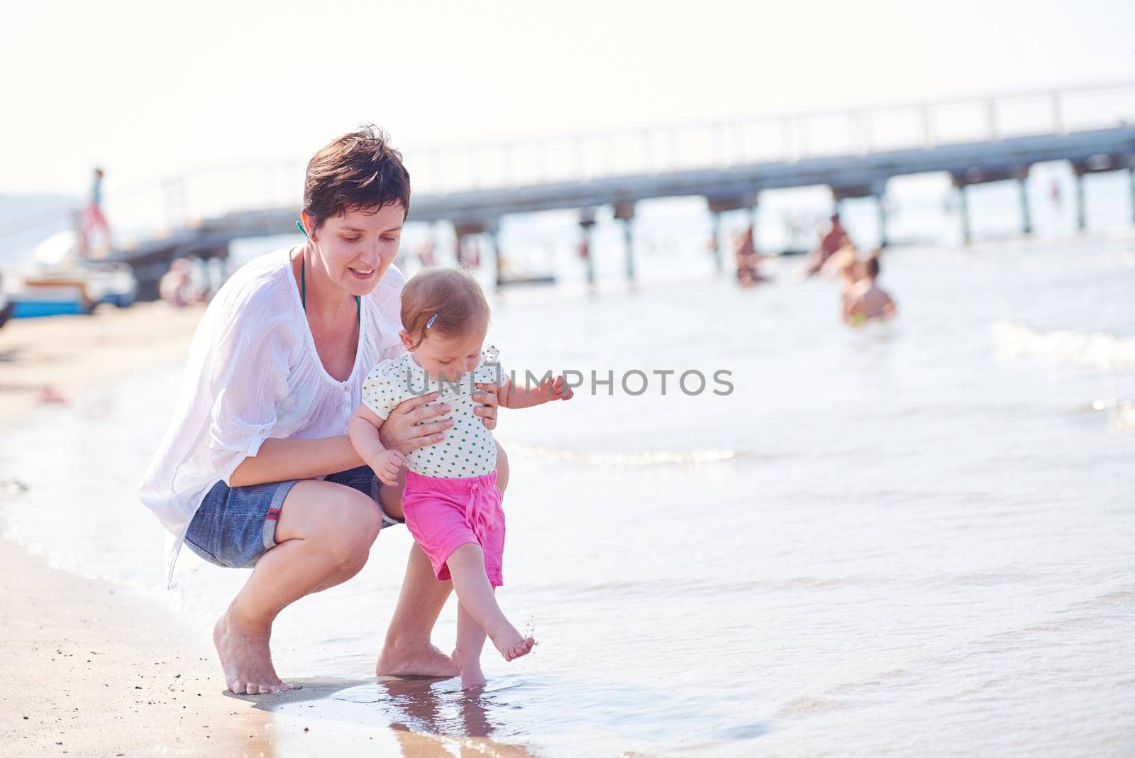 happy mom and baby on beach  have fun while learning to walk and  make first steps