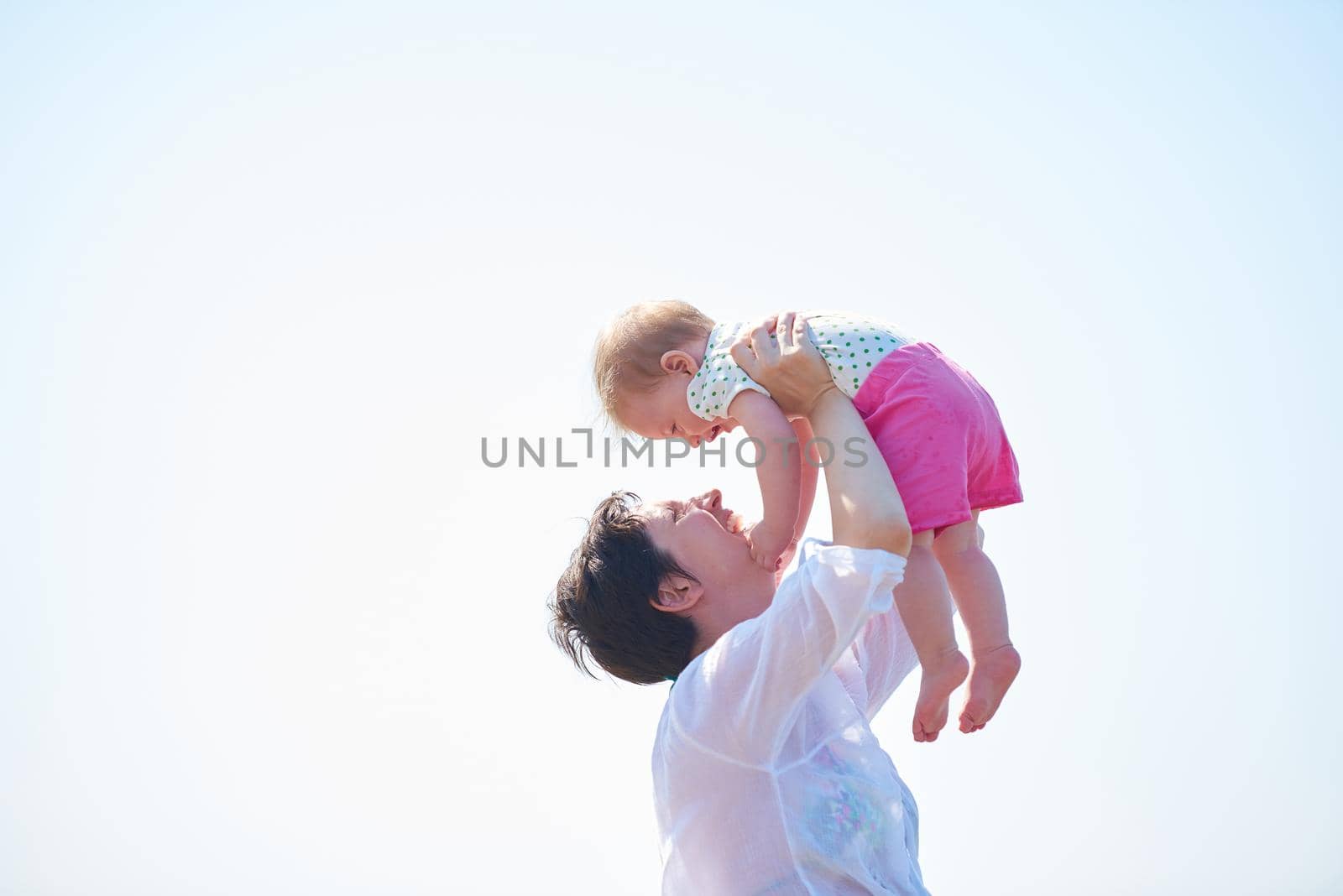 happy mom and baby on beach  have fun while learning to walk and  make first steps