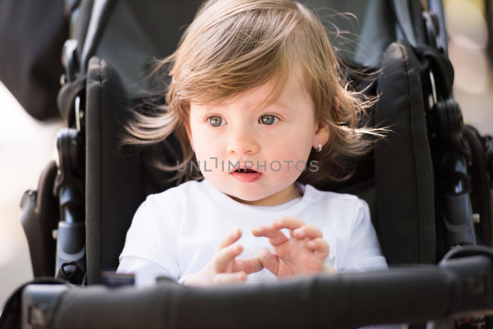 little and very beautiful baby girl sitting in the pram and waiting for mom