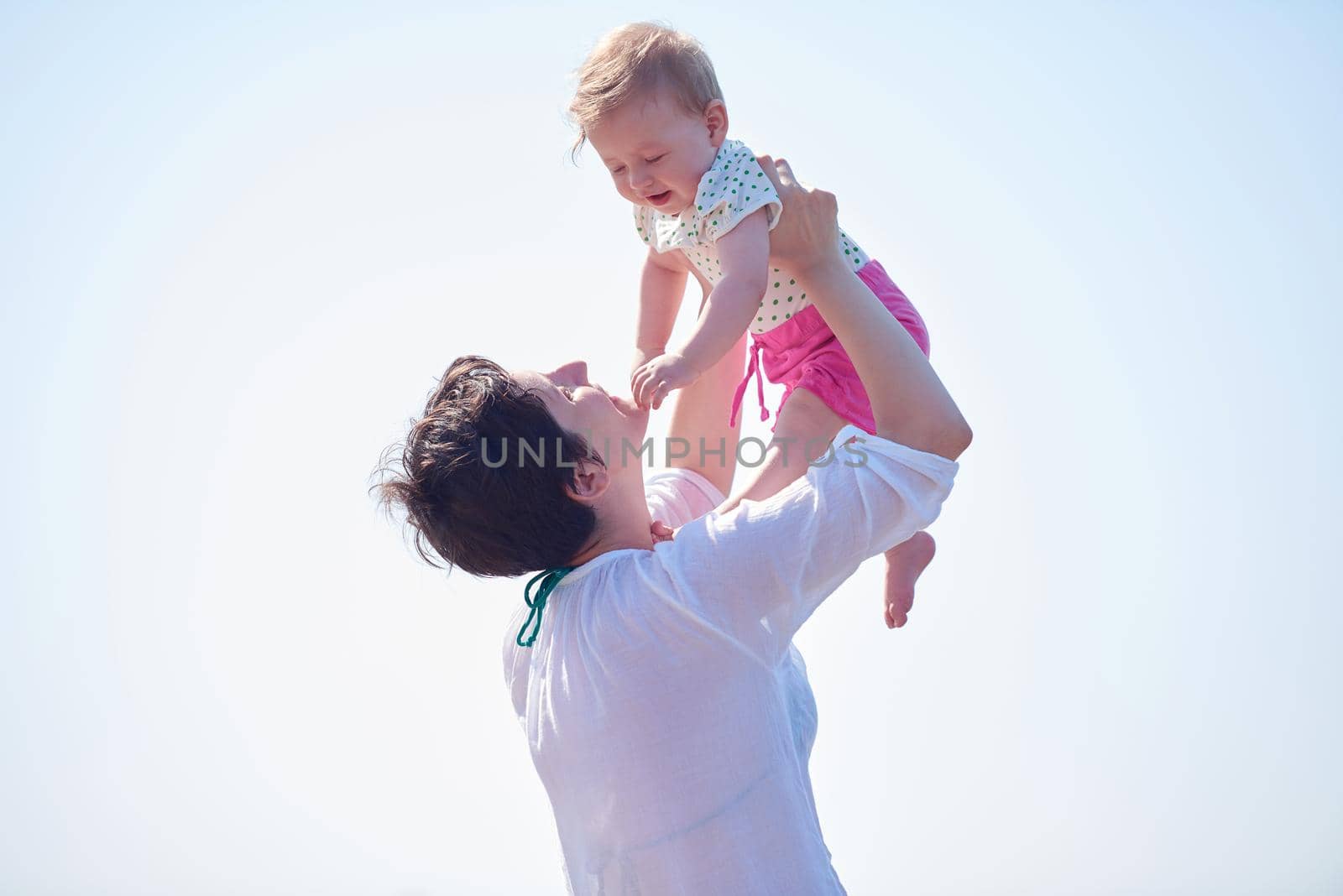 happy mom and baby on beach  have fun while learning to walk and  make first steps