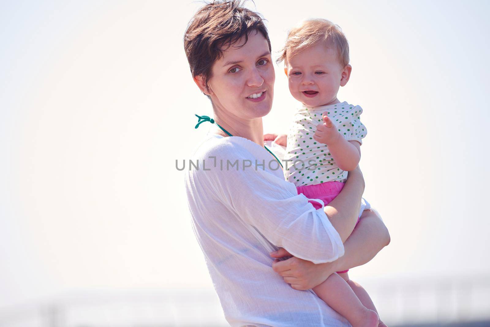 happy mom and baby on beach  have fun while learning to walk and  make first steps