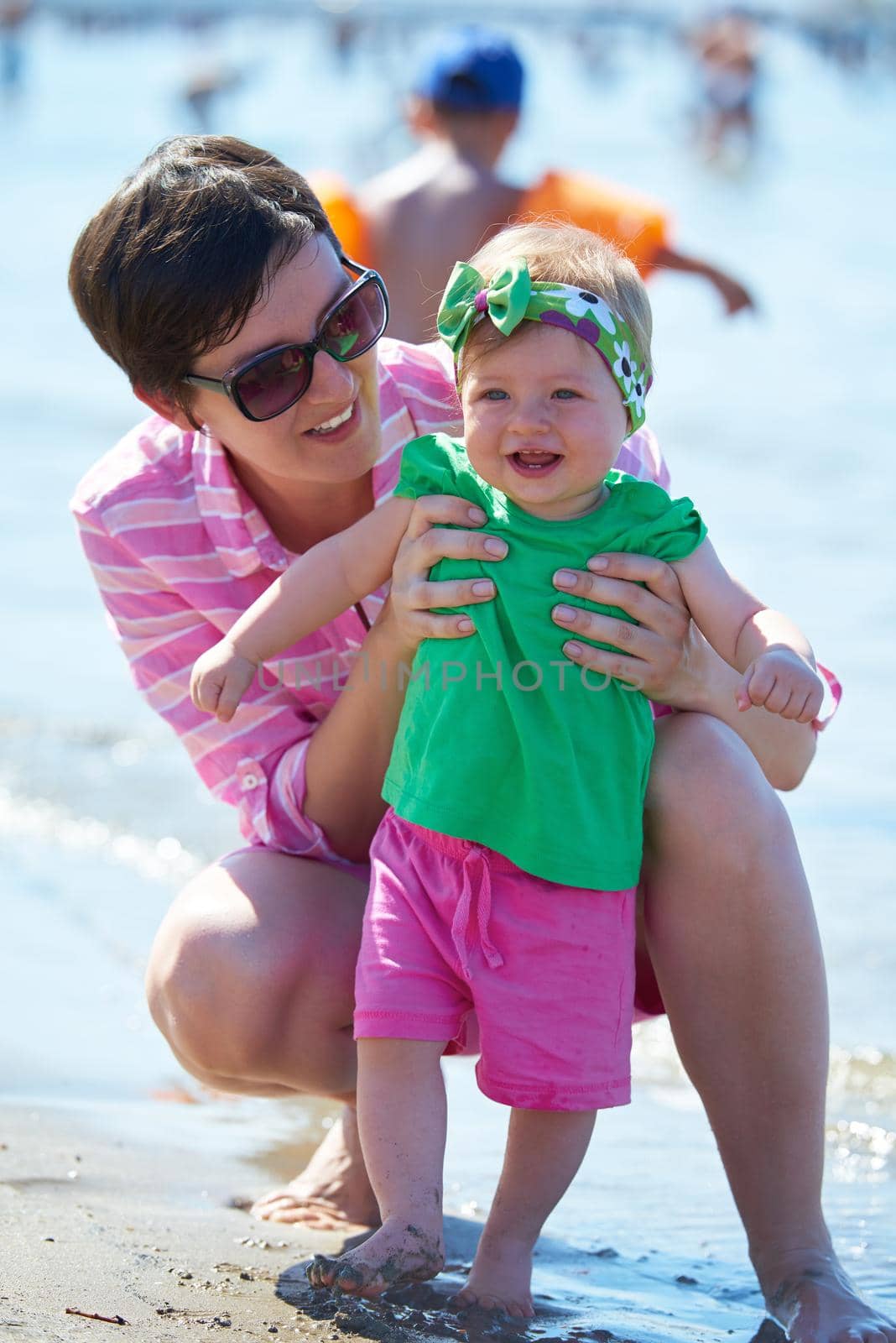 happy mom and baby on beach  have fun while learning to walk and  make first steps