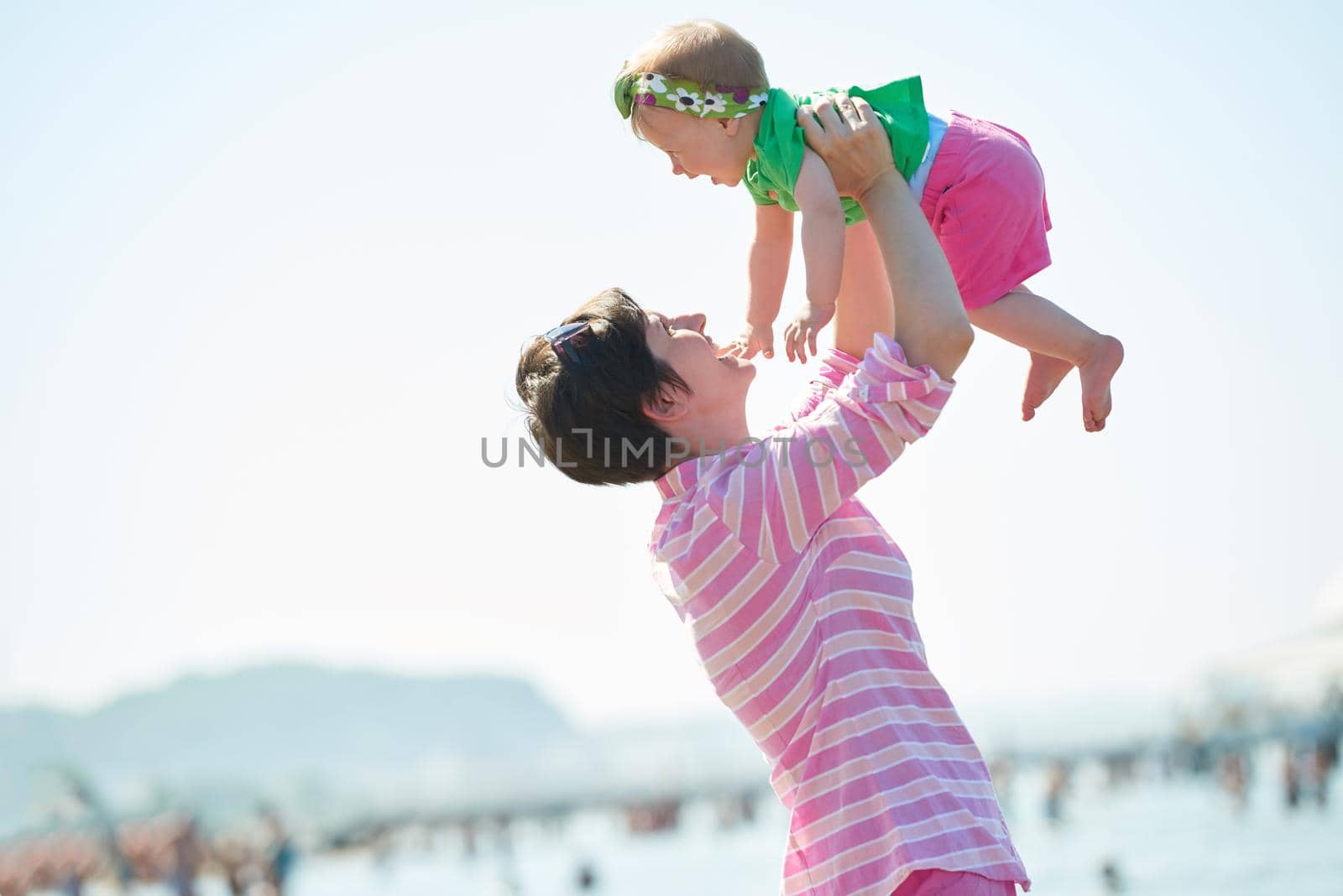 happy mom and baby on beach  have fun while learning to walk and  make first steps