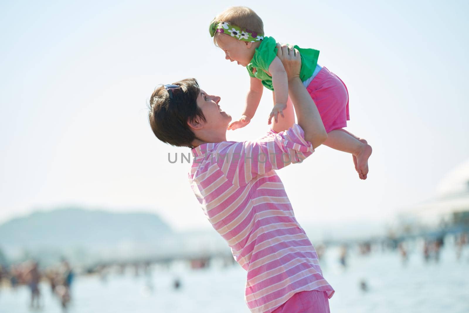 happy mom and baby on beach  have fun while learning to walk and  make first steps