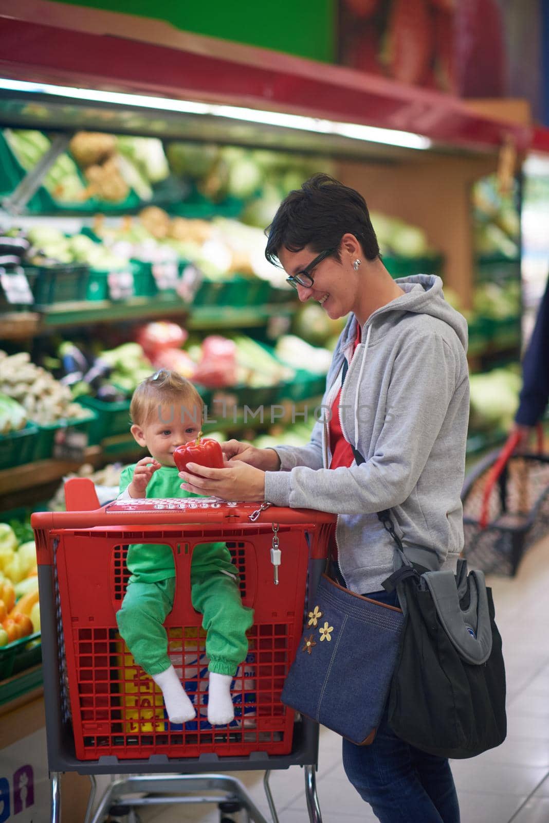 young mother with baby in shopping mall supermarket store buying food and grocery