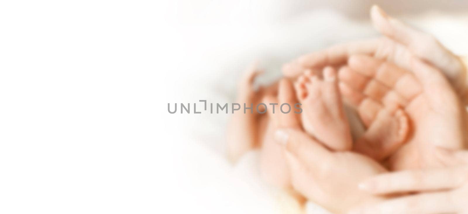 blurred image for the advertising text. photo with copy space. legs newborn baby in the hands of his parents by SmartPhotoLab