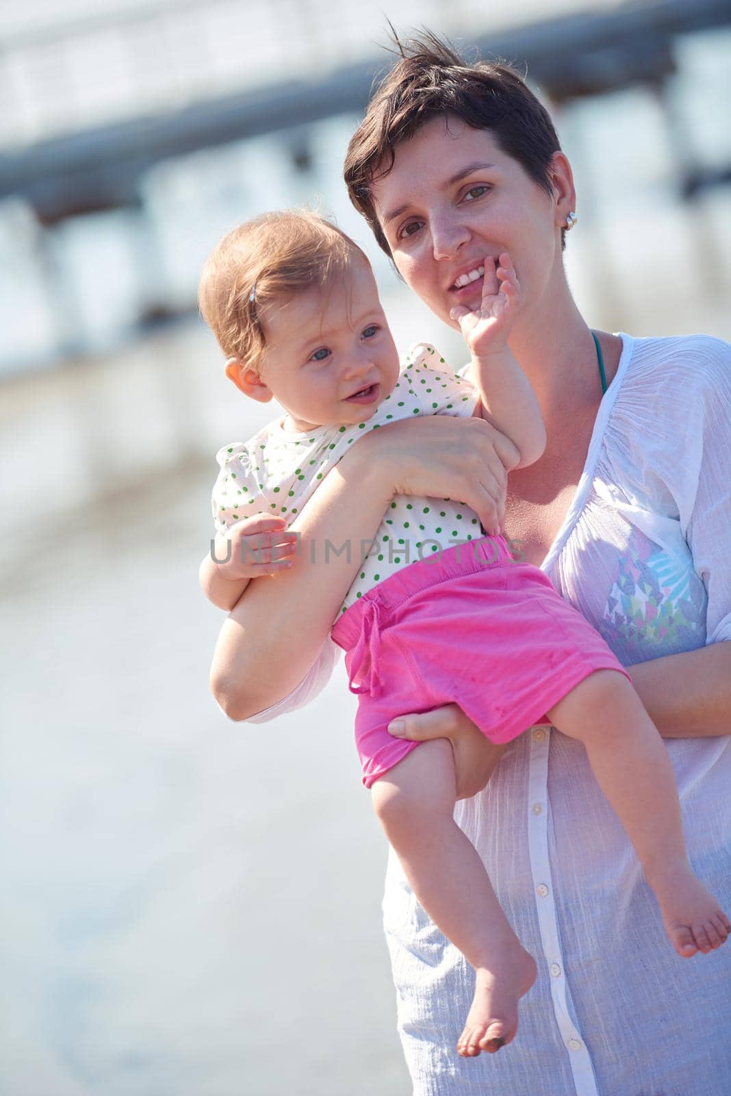 happy mom and baby on beach  have fun while learning to walk and  make first steps