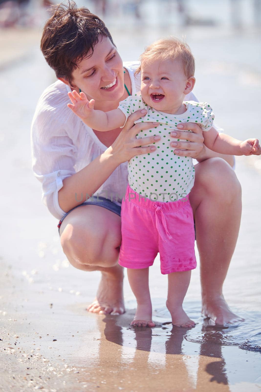 happy mom and baby on beach  have fun while learning to walk and  make first steps