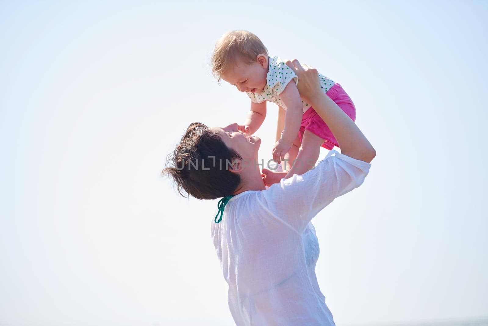 happy mom and baby on beach  have fun while learning to walk and  make first steps