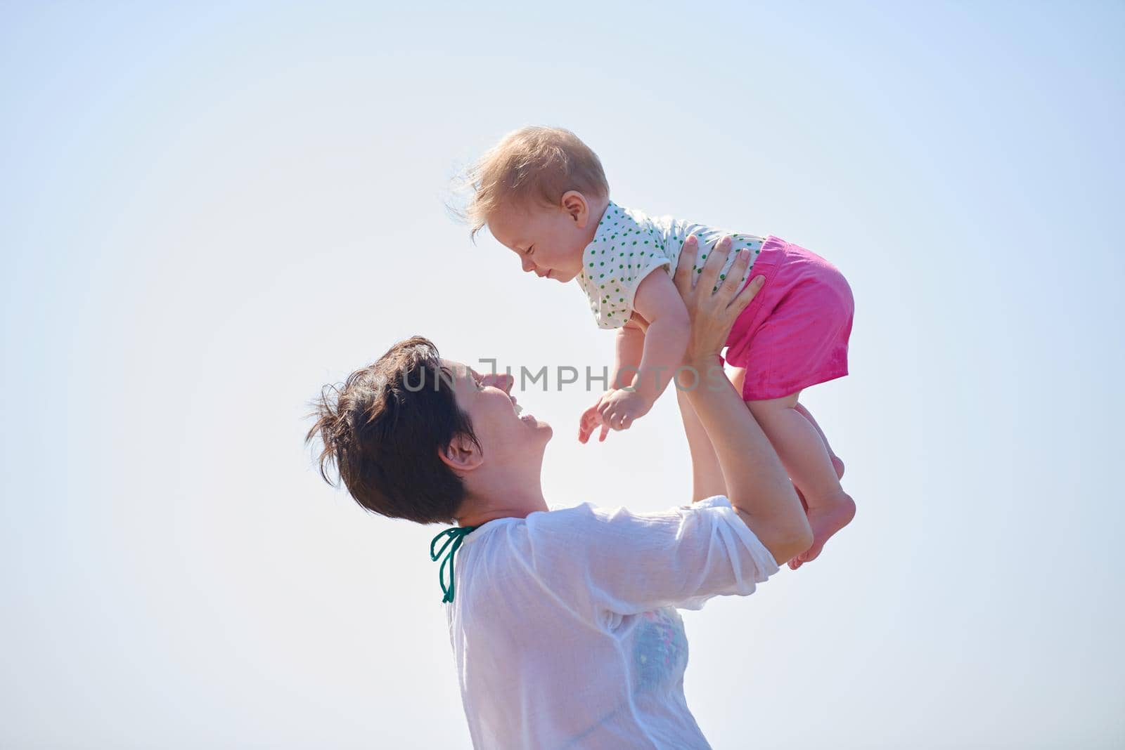 happy mom and baby on beach  have fun while learning to walk and  make first steps