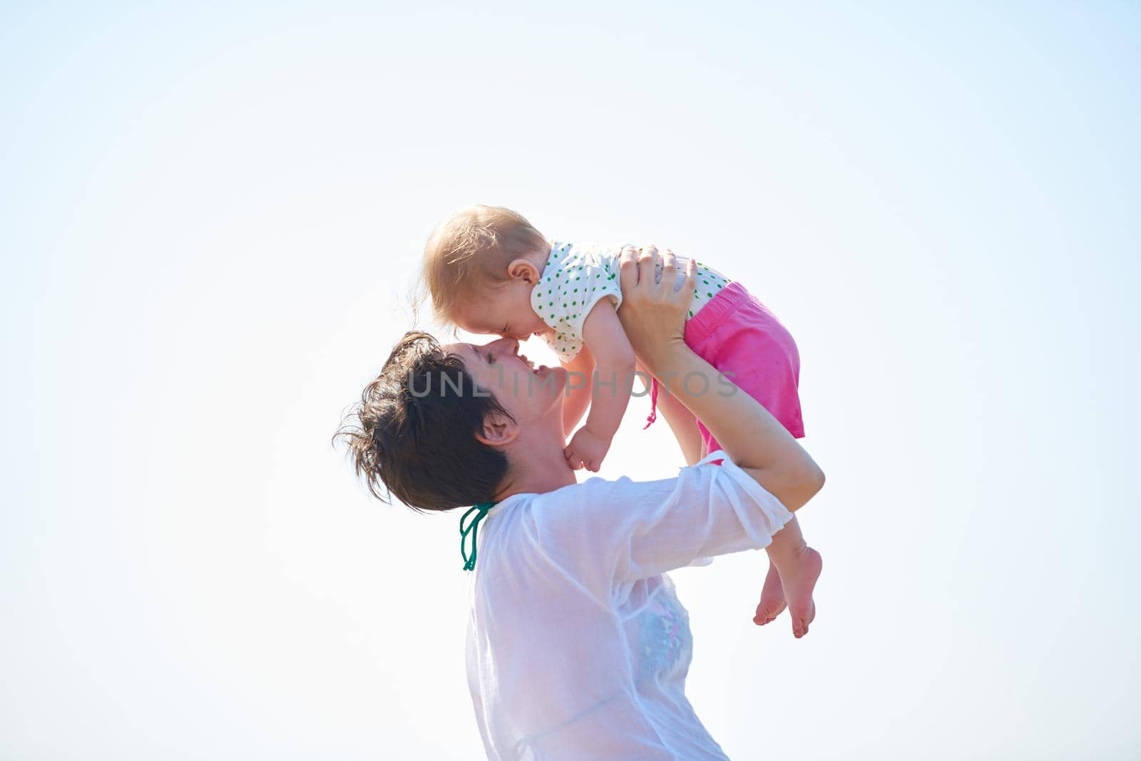 happy mom and baby on beach  have fun while learning to walk and  make first steps