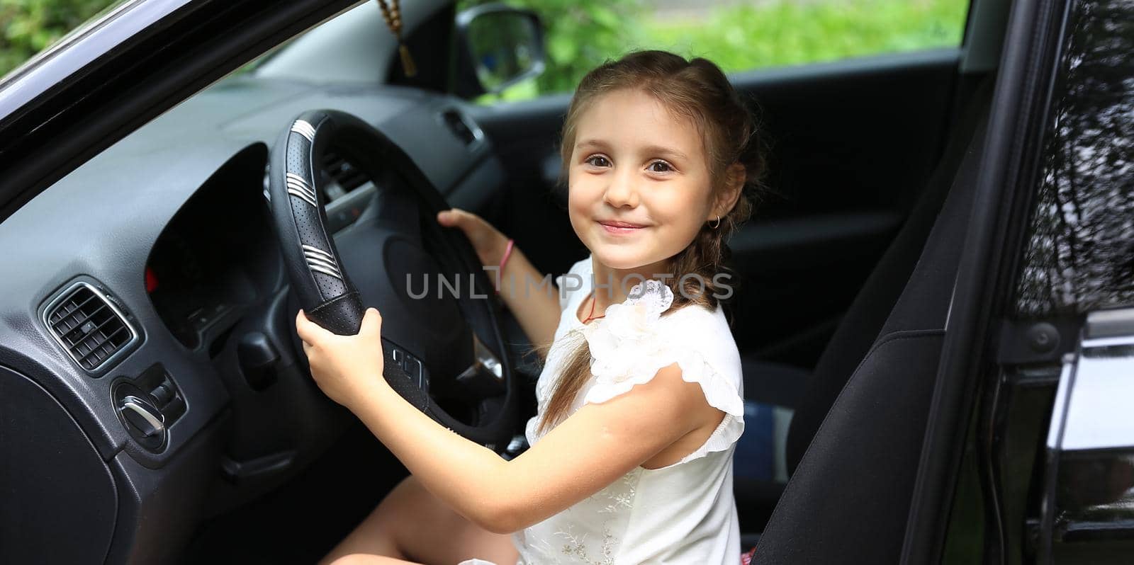 happy little girl sitting behind the wheel of dad's car.the concept of happiness