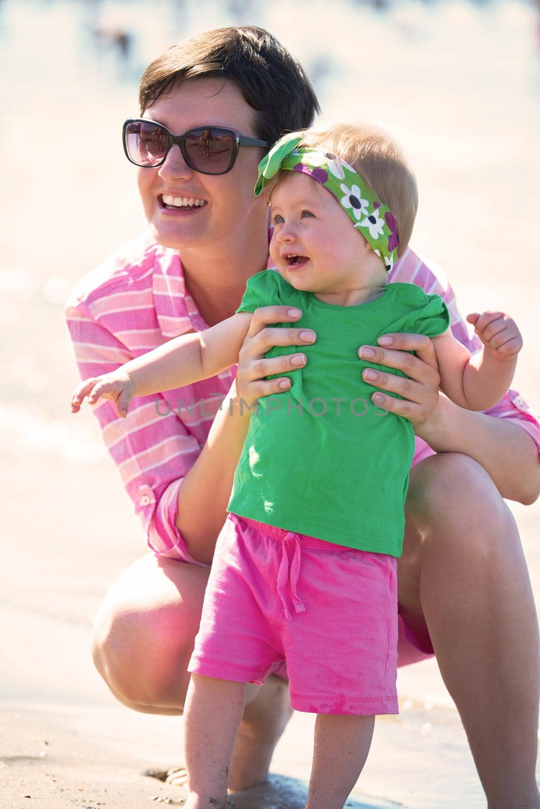 happy mom and baby on beach  have fun while learning to walk and  make first steps