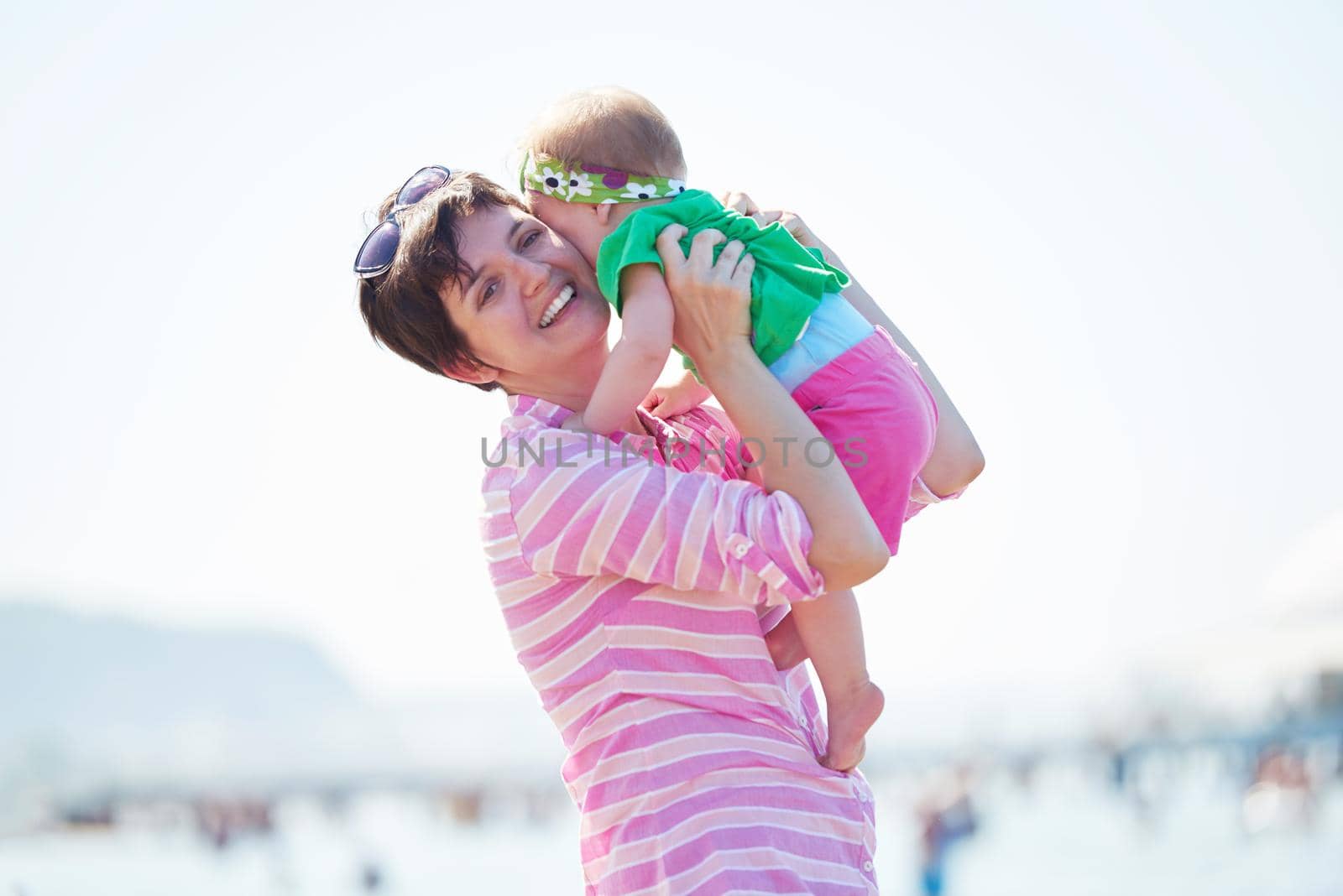 happy mom and baby on beach  have fun while learning to walk and  make first steps