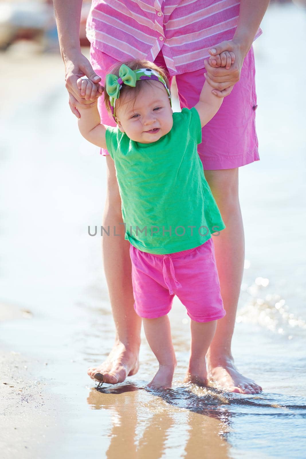 happy mom and baby on beach  have fun while learning to walk and  make first steps