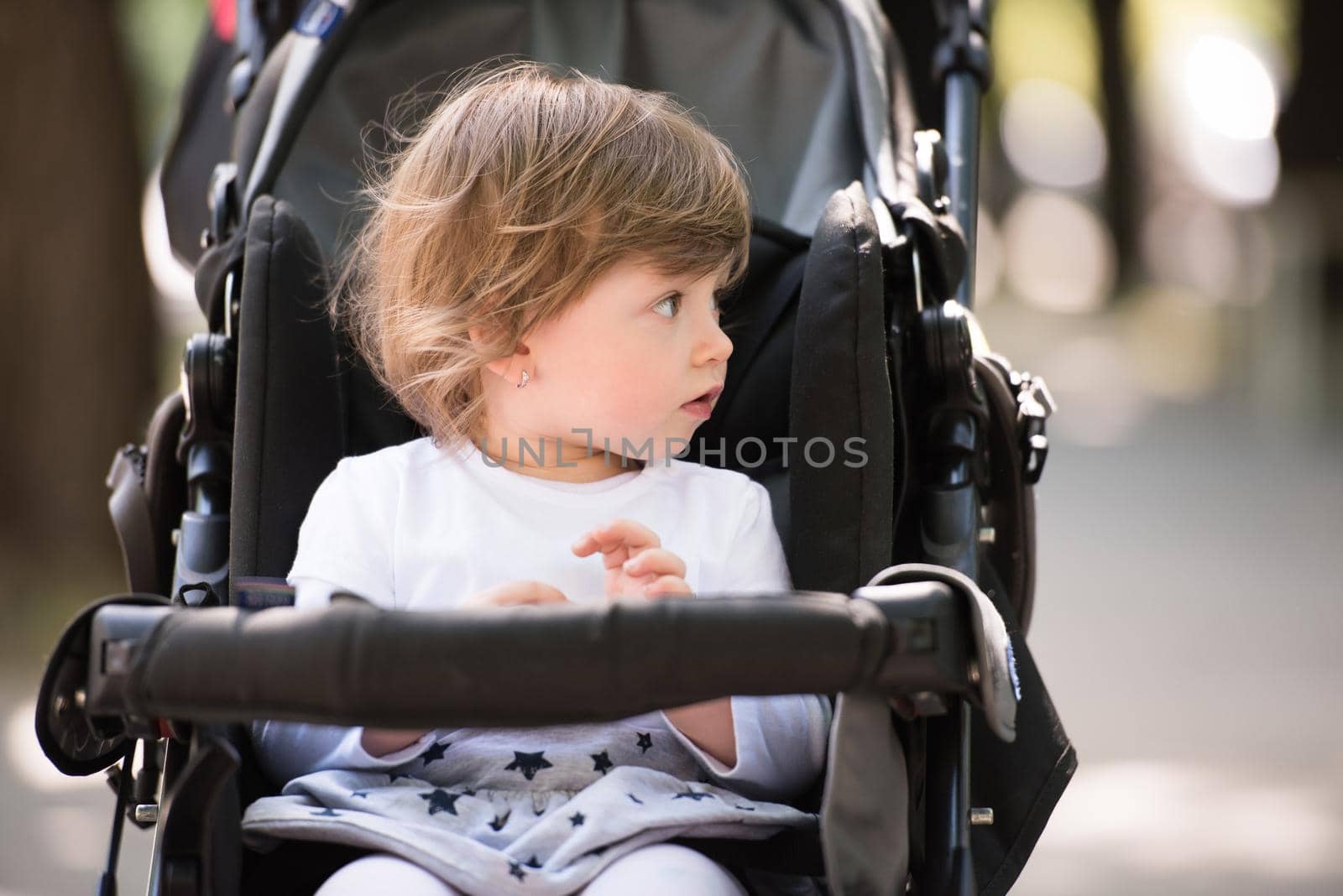 little and very beautiful baby girl sitting in the pram and waiting for mom