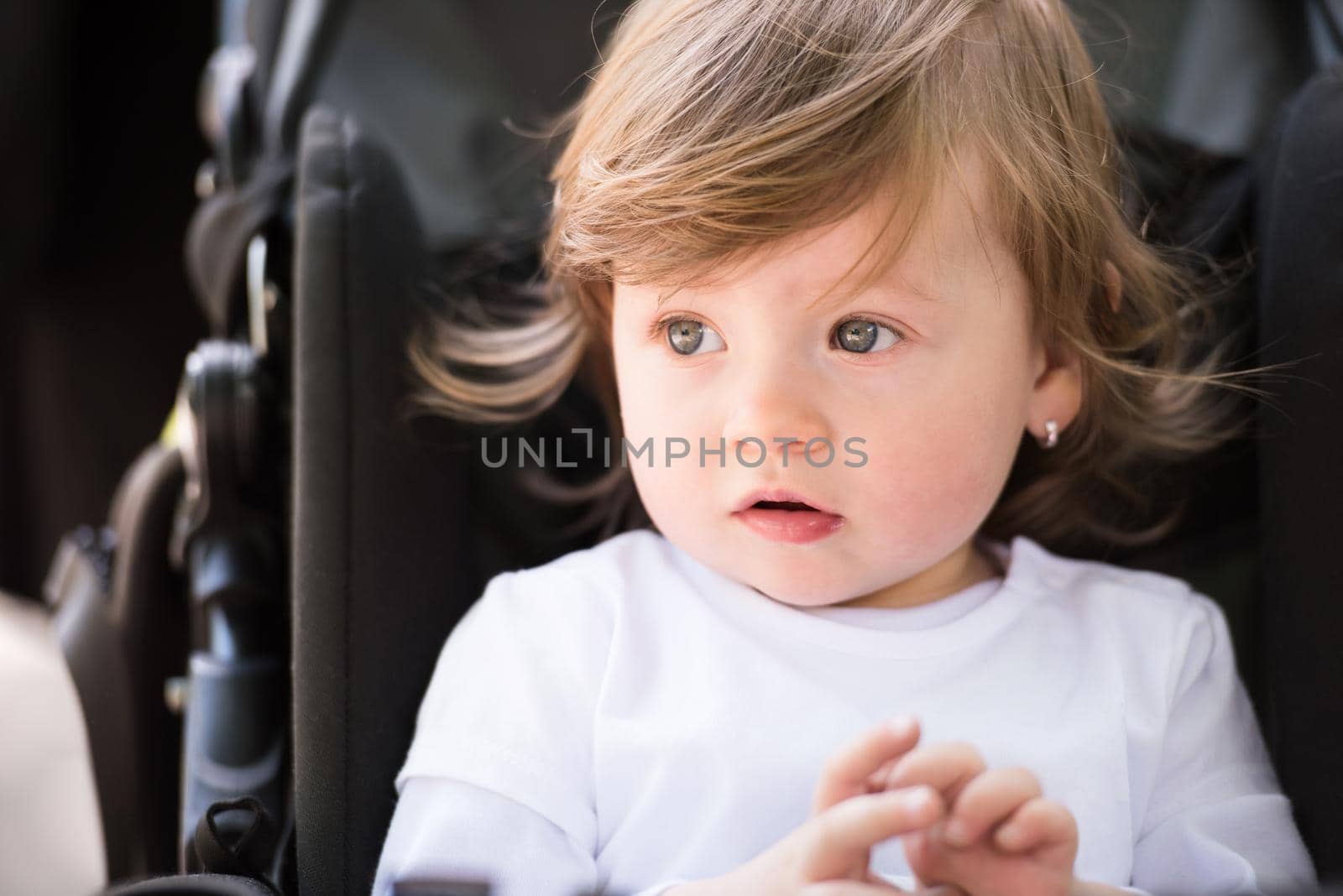 little and very beautiful baby girl sitting in the pram and waiting for mom