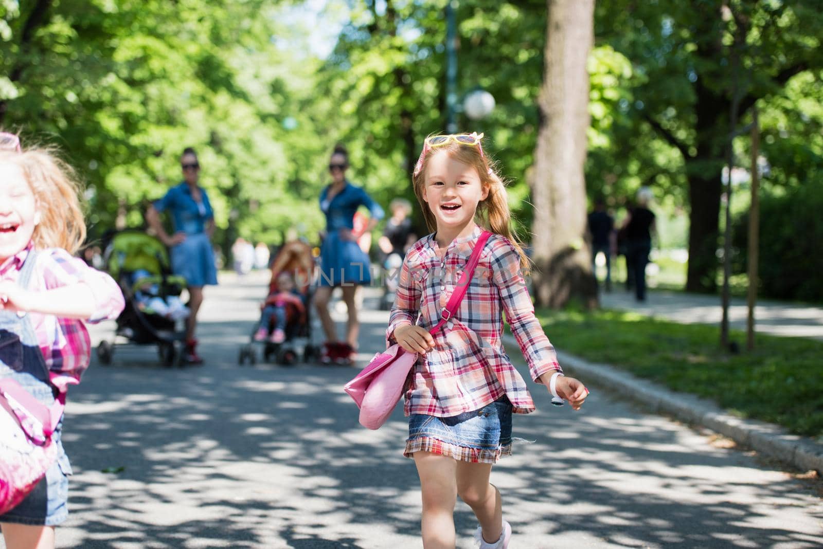 Young beautiful twins mother with children enjoying a sunny day in city park