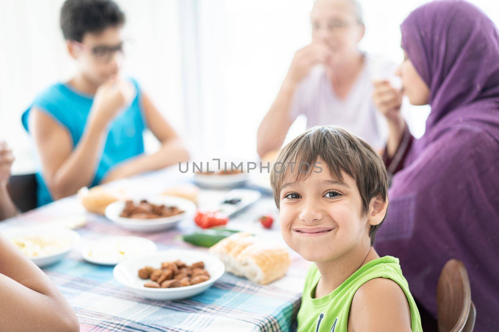 Happy family enjoying eating food in dining room together by Zurijeta