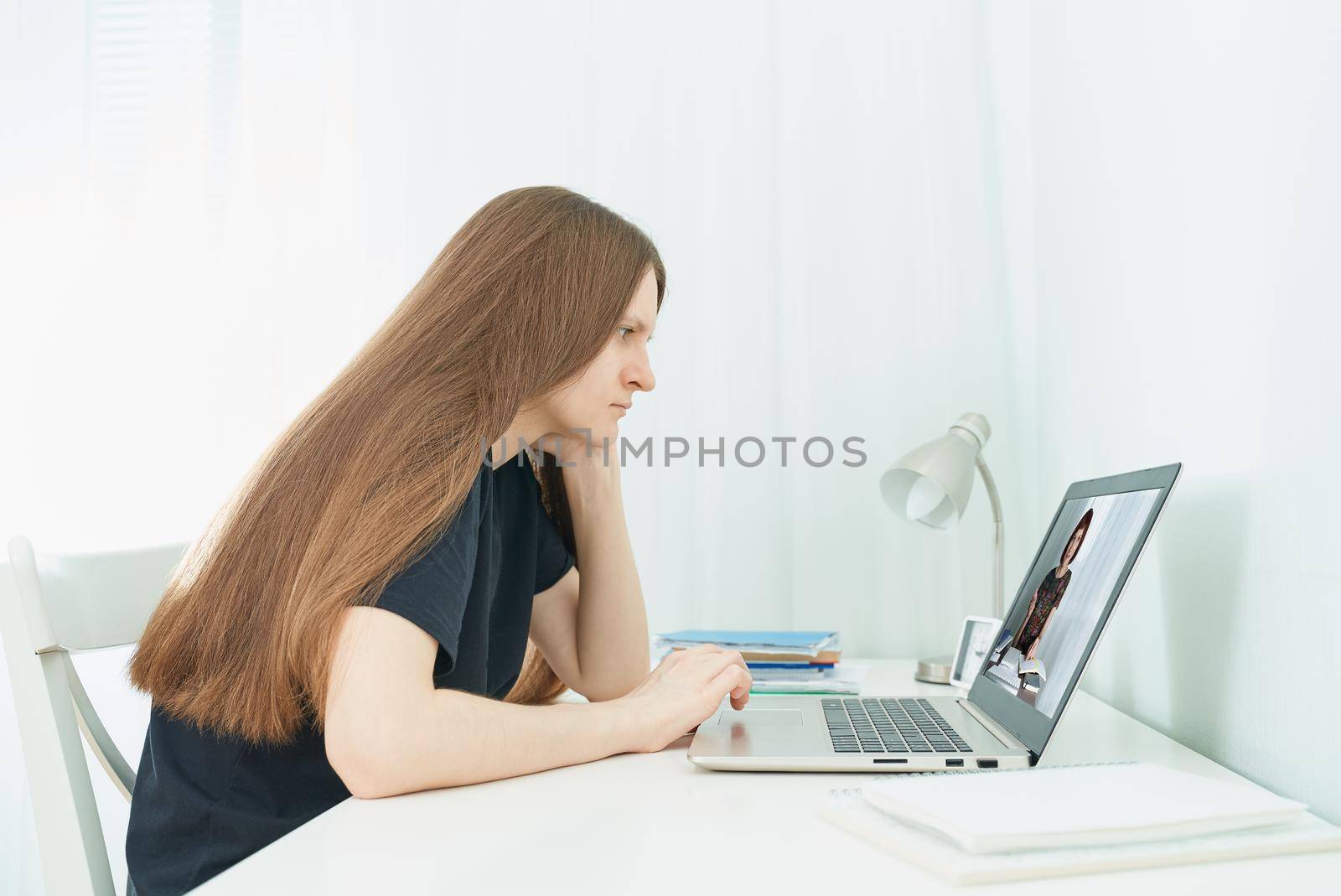 Distance education for students. Quarantine, self-isolation, sociophobia. Young girl listens to online learning, teleworking, online lectures.Woman look at laptop. Freelancer, Digital Nomad Concept