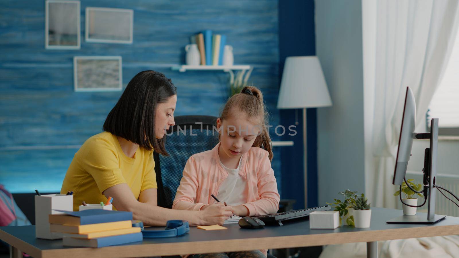 Schoolgirl and parent doing homework together with monitor by DCStudio