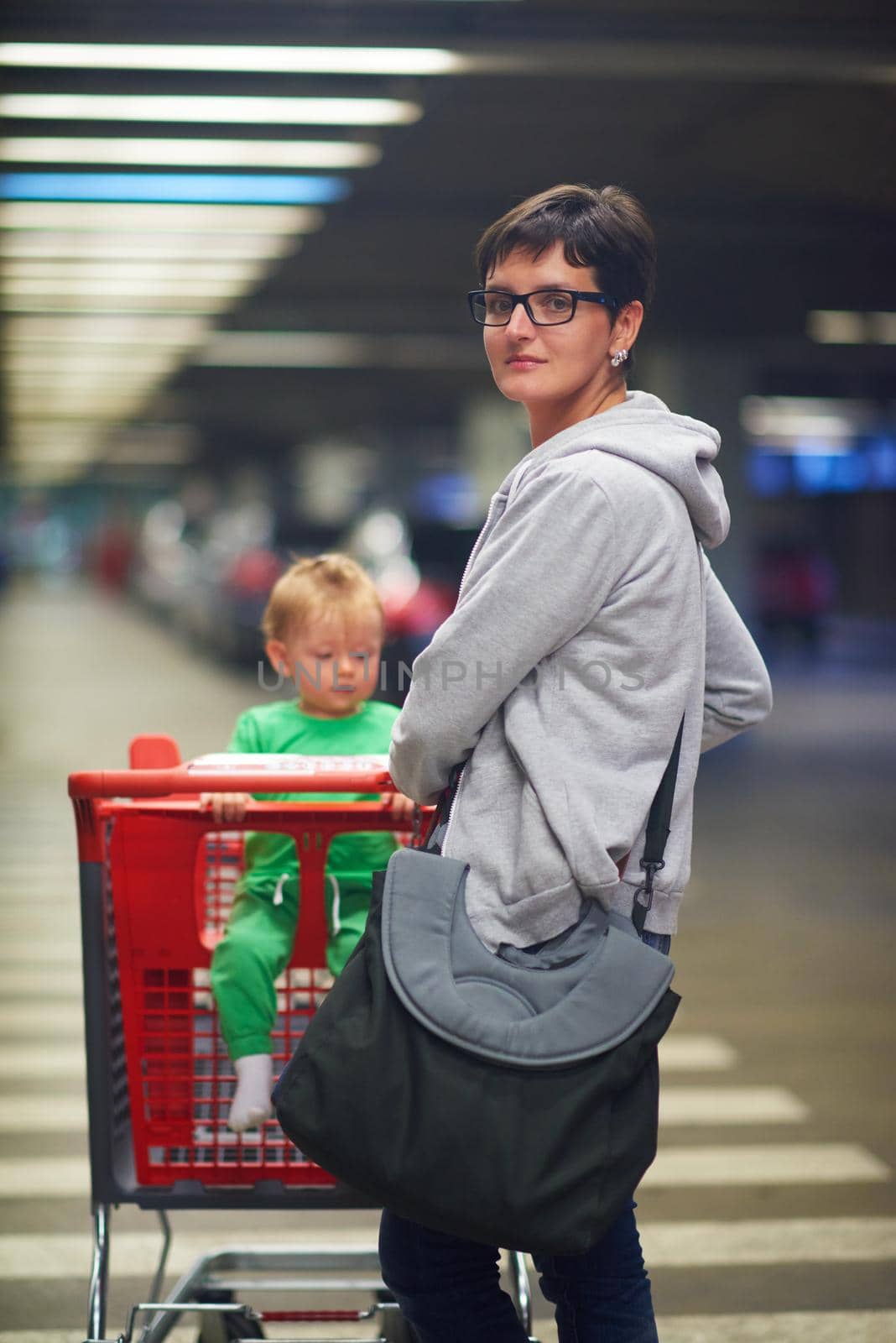 young mother with baby in shopping mall supermarket store buying food and grocery