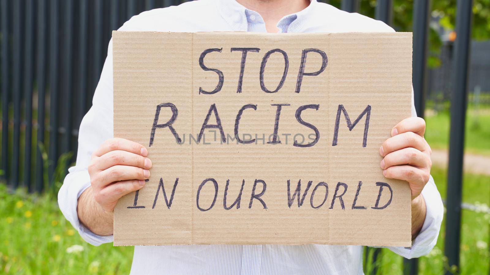 Stop racism concept. Unrecognizable person holds sign with text against racist. White people protests in demonstration