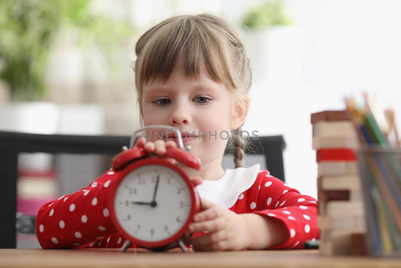 Cute child learn how to understand time and play with red retro clock by kuprevich
