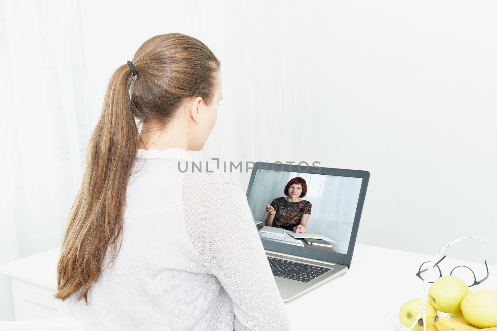 Distance learning for students. Quarantine, self-isolation, social phobia. Young girl listens to online training, telework, rear view. Woman looks at laptop. Freelancer, Concept Of Digital Nomad