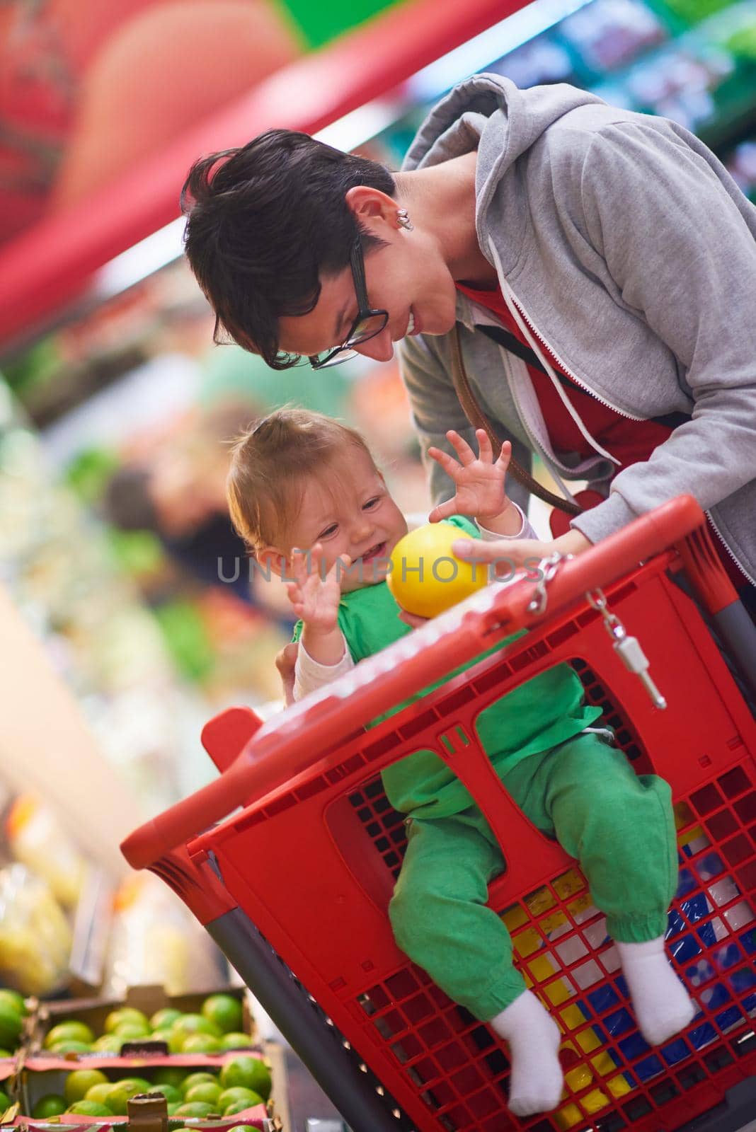 young mother with baby in shopping mall supermarket store buying food and grocery