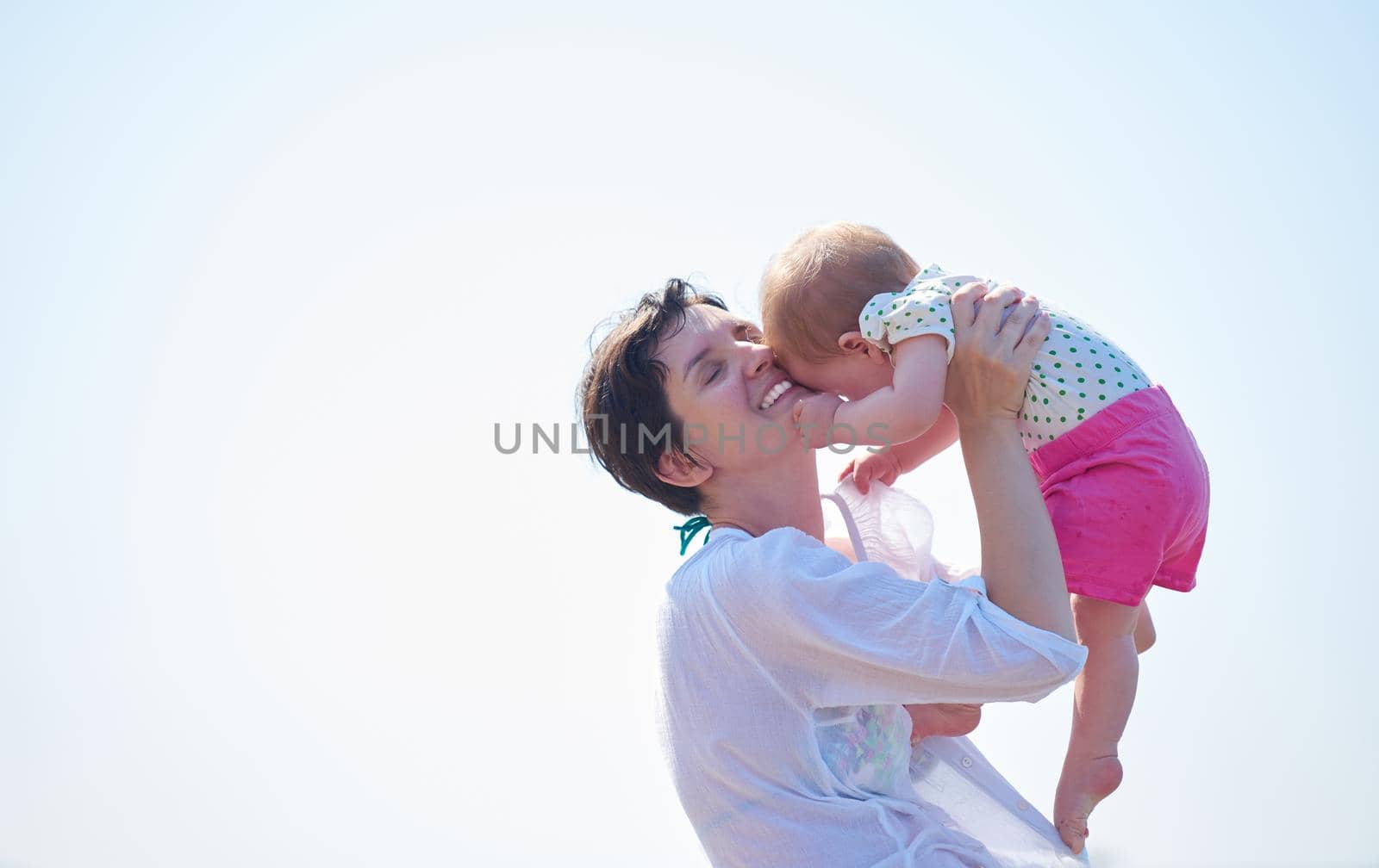 happy mom and baby on beach  have fun while learning to walk and  make first steps