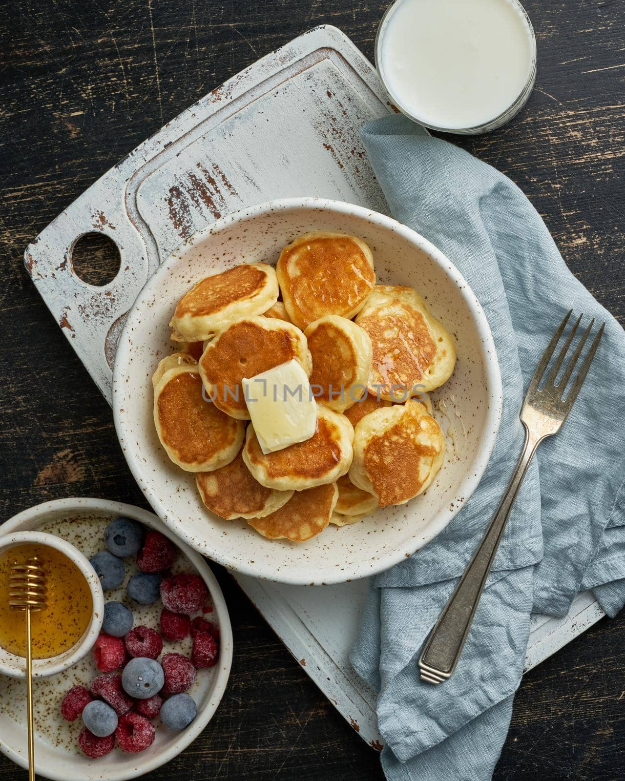 Pancakes cereal, tiny thin funny crumpet, children's food. Breakfast with drink, dark table by NataBene