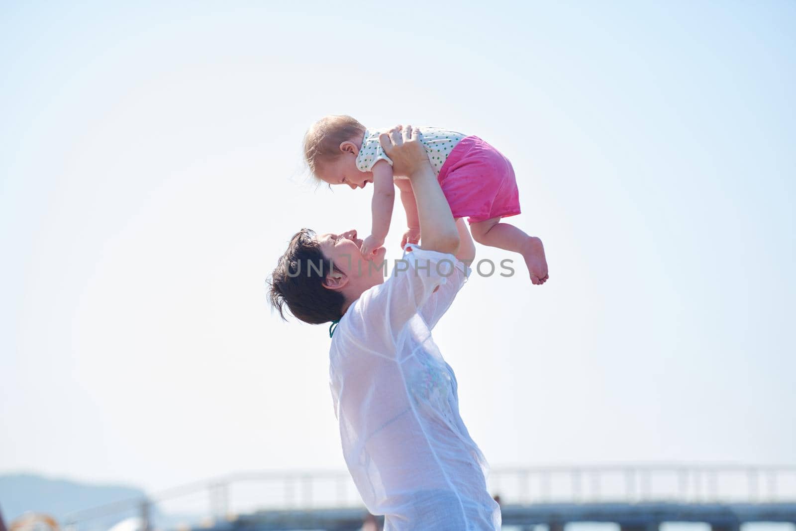 happy mom and baby on beach  have fun while learning to walk and  make first steps