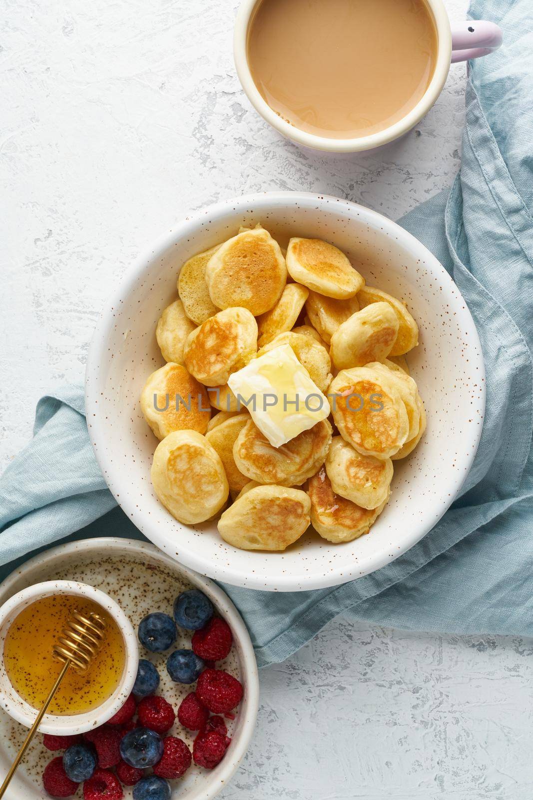 Pancakes cereal, tiny thin funny crumpet, children's food. Breakfast with drink, white table, bright morning, top view, vertical