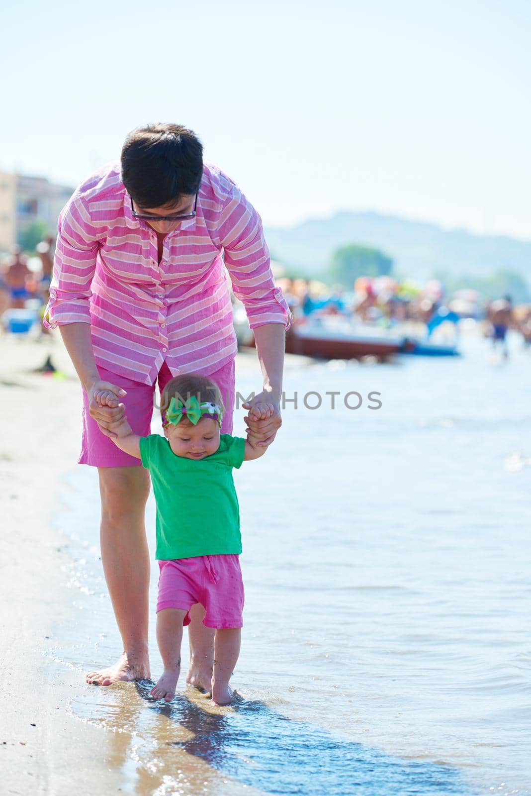 happy mom and baby on beach  have fun while learning to walk and  make first steps