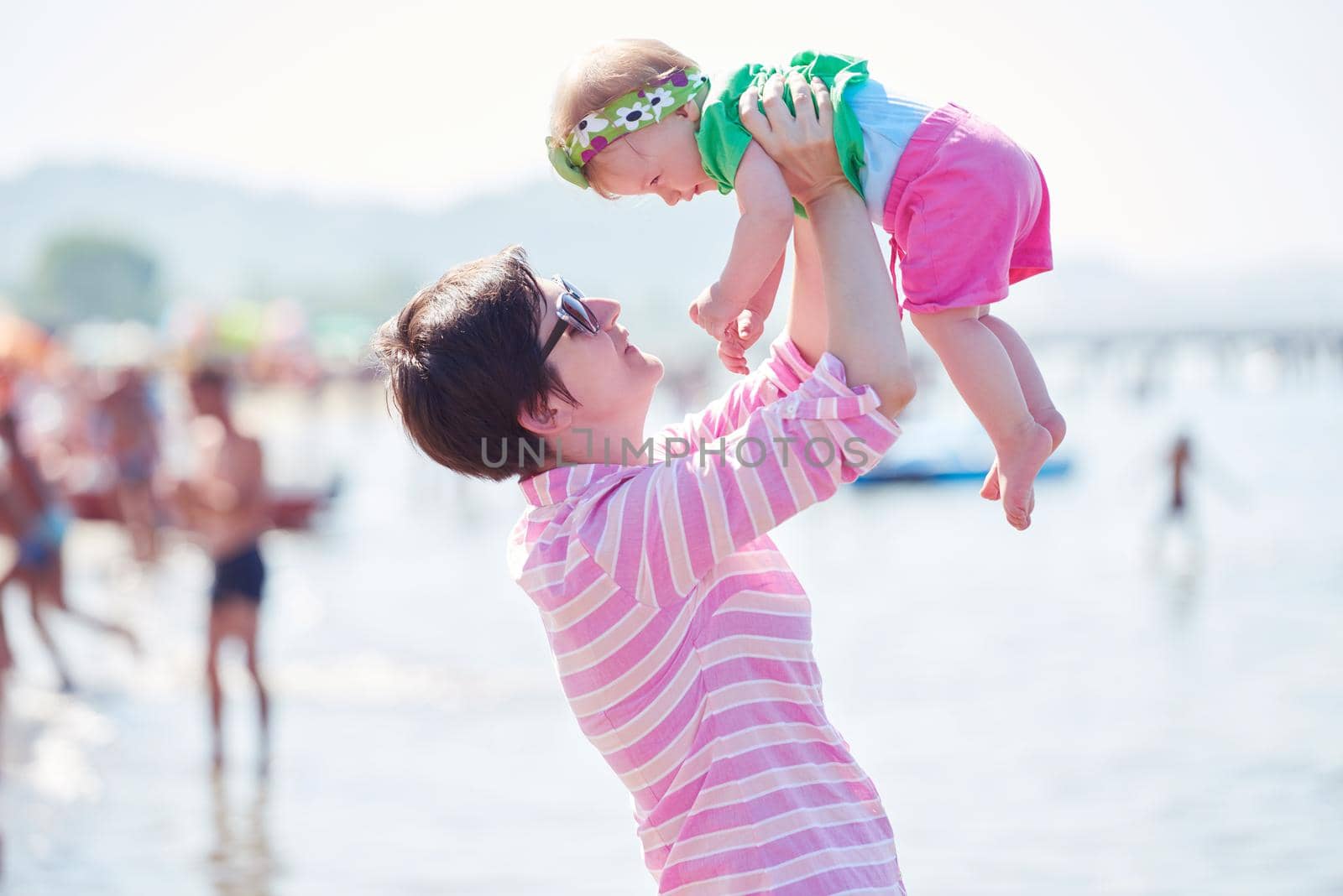 happy mom and baby on beach  have fun while learning to walk and  make first steps