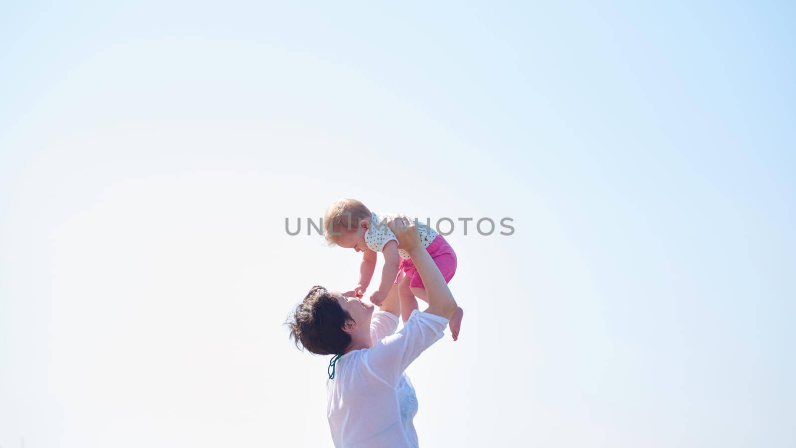 happy mom and baby on beach  have fun while learning to walk and  make first steps