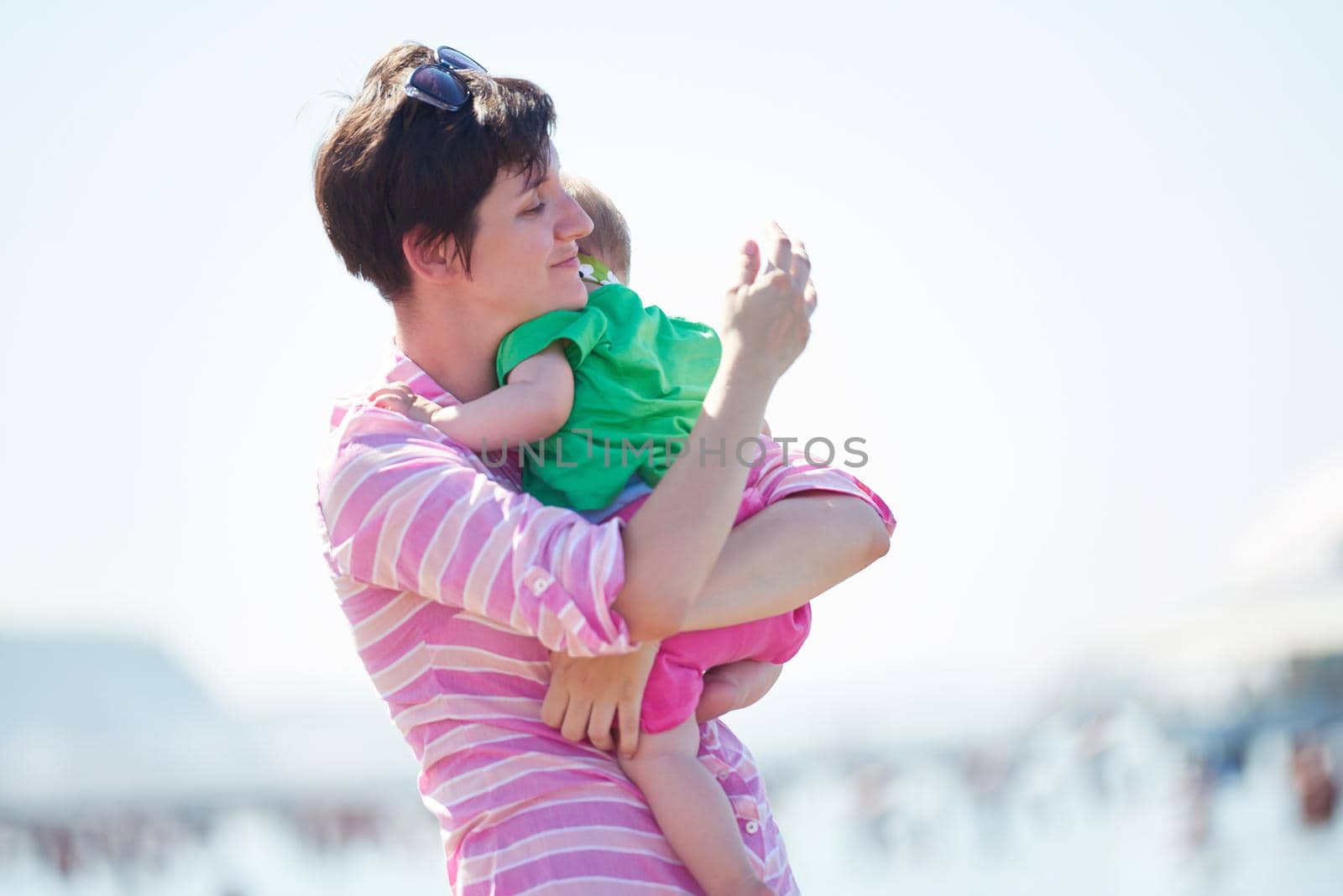 happy mom and baby on beach  have fun while learning to walk and  make first steps