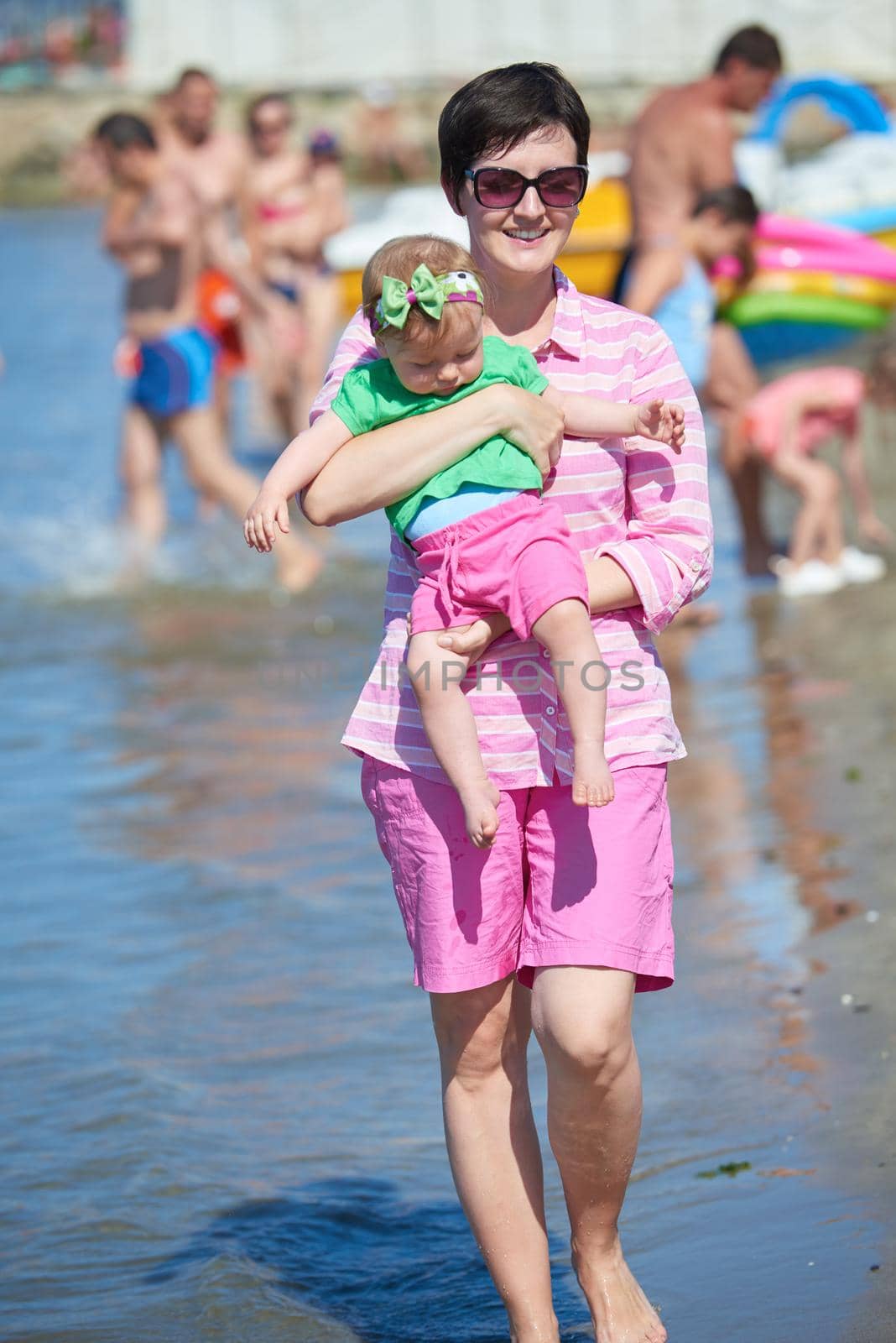 happy mom and baby on beach  have fun while learning to walk and  make first steps