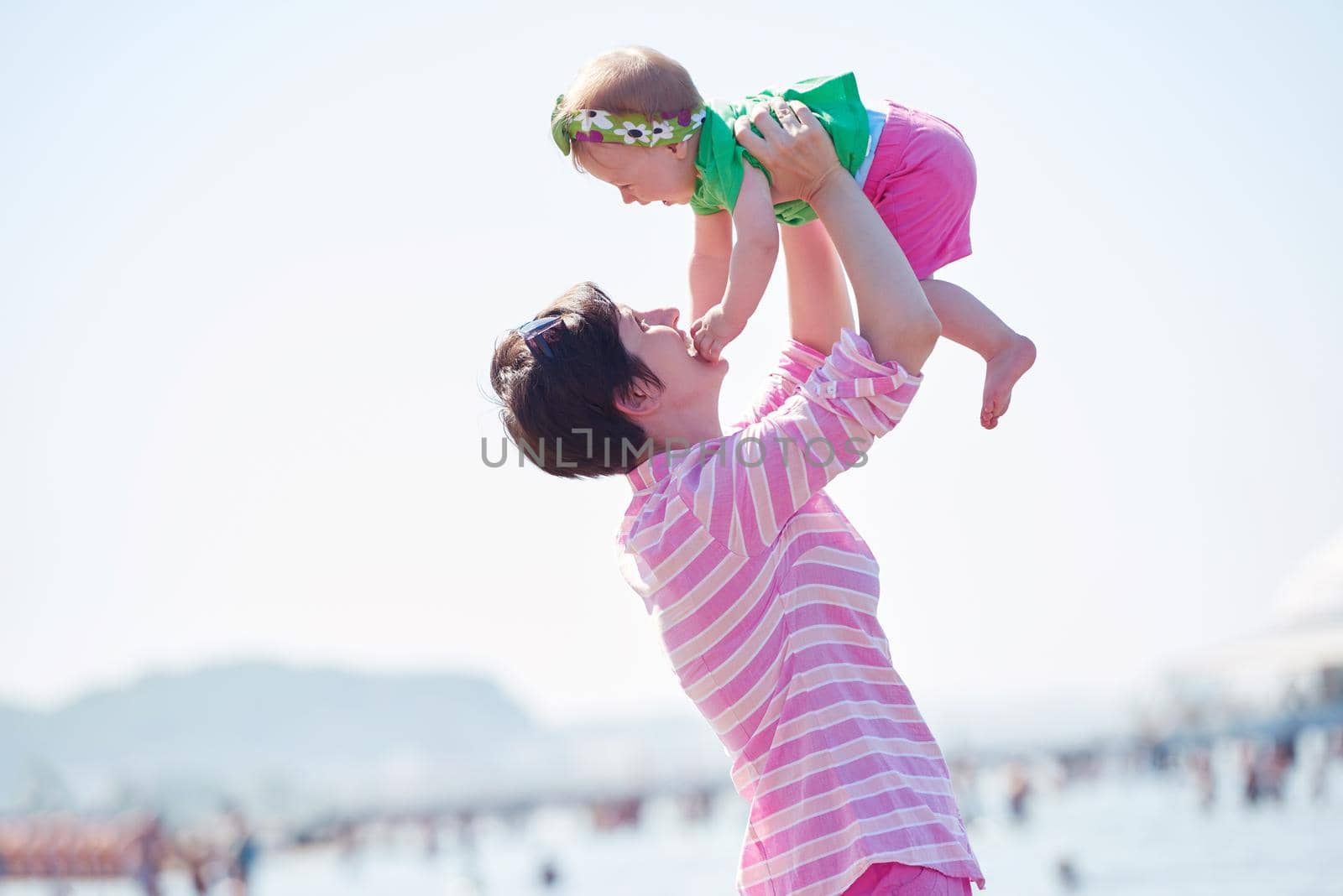 happy mom and baby on beach  have fun while learning to walk and  make first steps