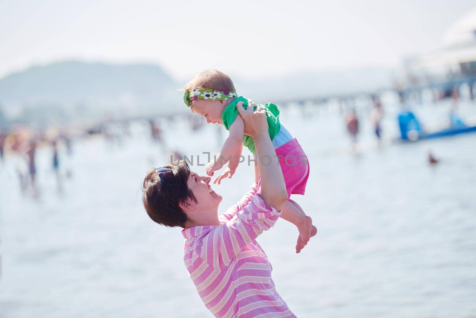 happy mom and baby on beach  have fun while learning to walk and  make first steps