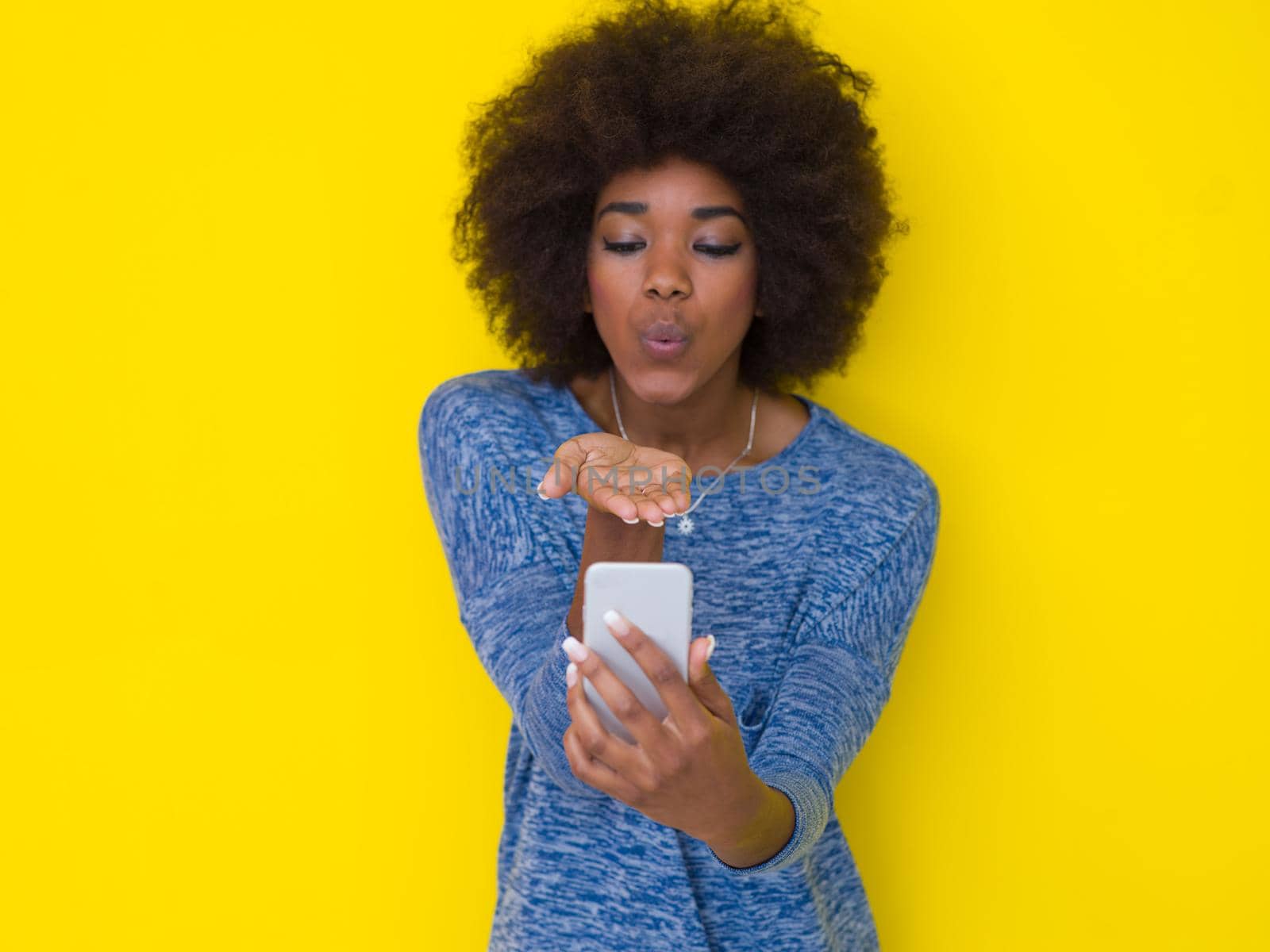 Young Happy African American Woman Using mobile phone  Isolated on a yellow background