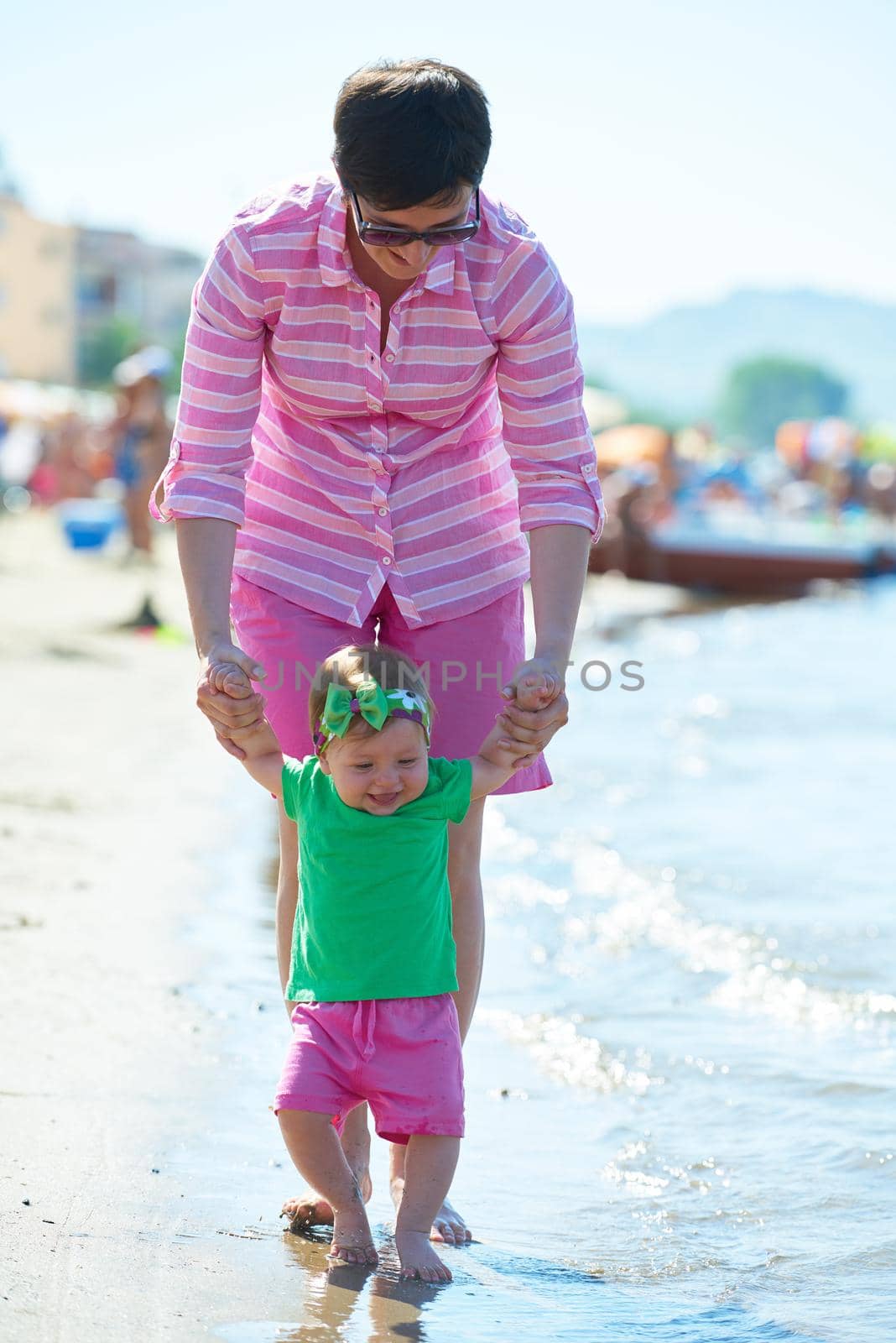 happy mom and baby on beach  have fun while learning to walk and  make first steps