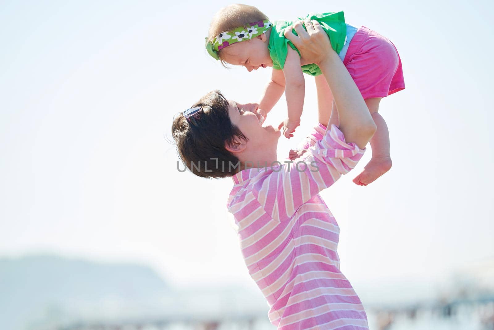 happy mom and baby on beach  have fun while learning to walk and  make first steps