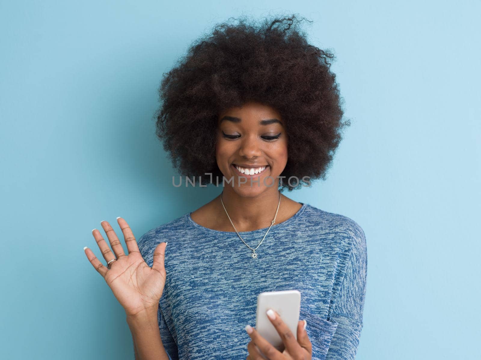 Young Happy African American Woman Using mobile phone  Isolated on a blue background