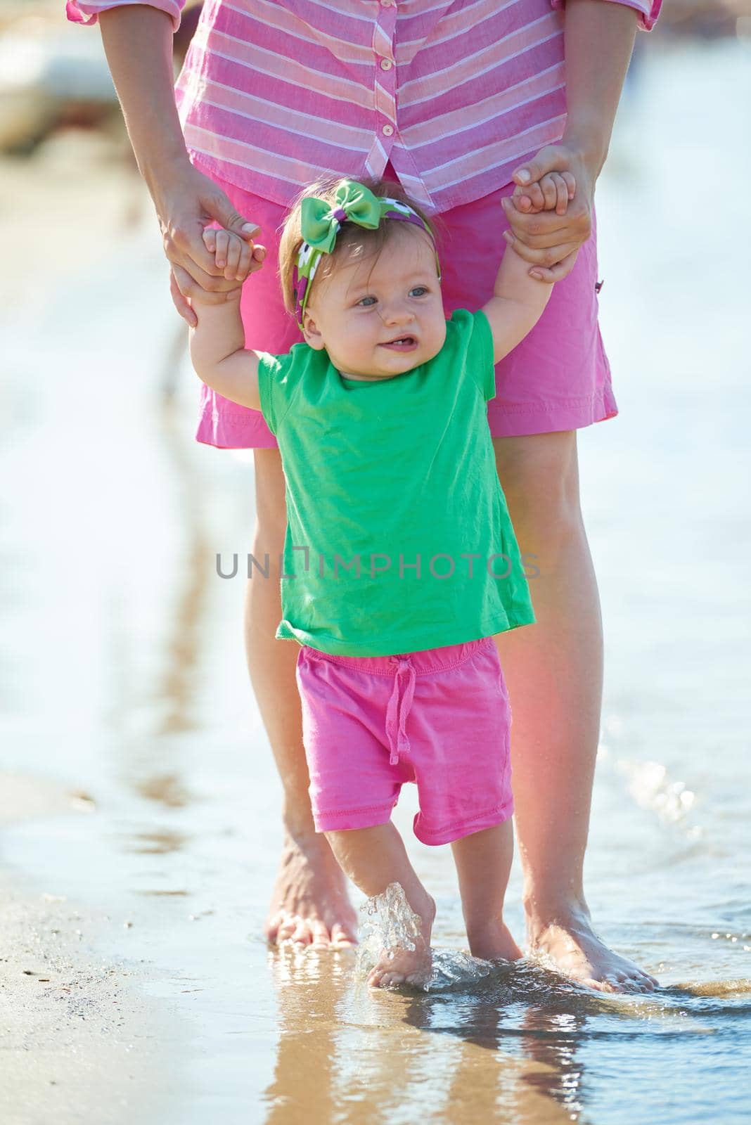 happy mom and baby on beach  have fun while learning to walk and  make first steps